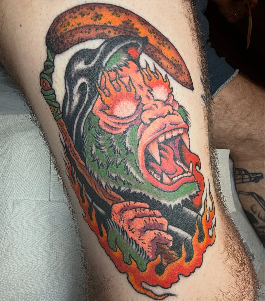 This tattoo features a fierce gorilla with an expressive face, surrounded by flames.