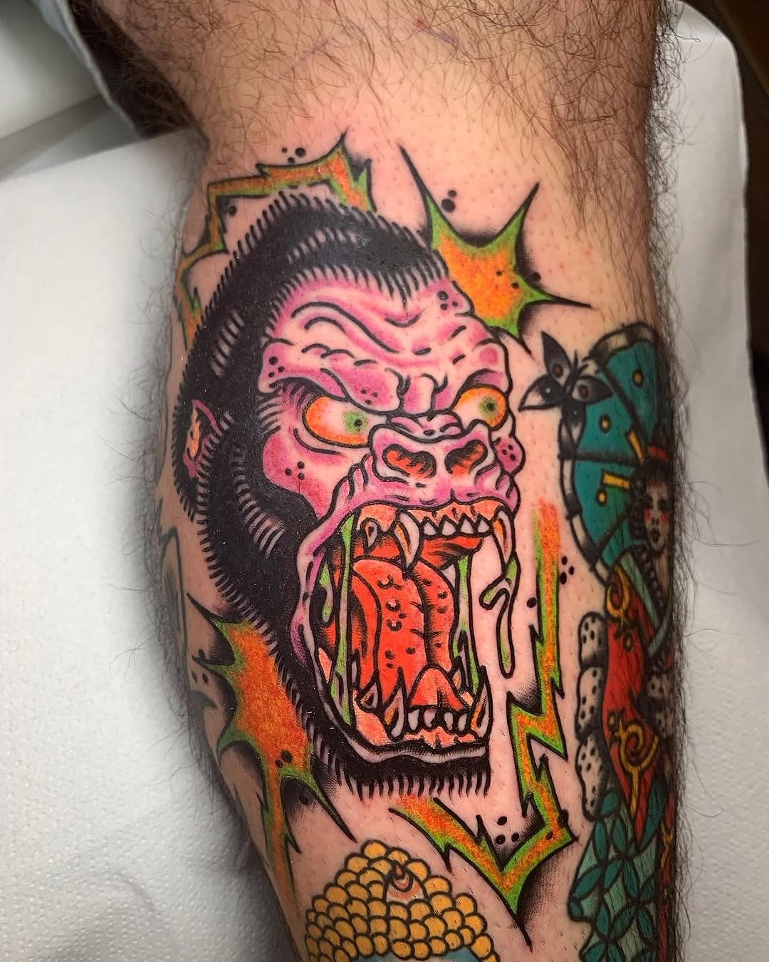 This striking gorilla tattoo features vivid colors, showing a roaring gorilla with wild, expressive features.