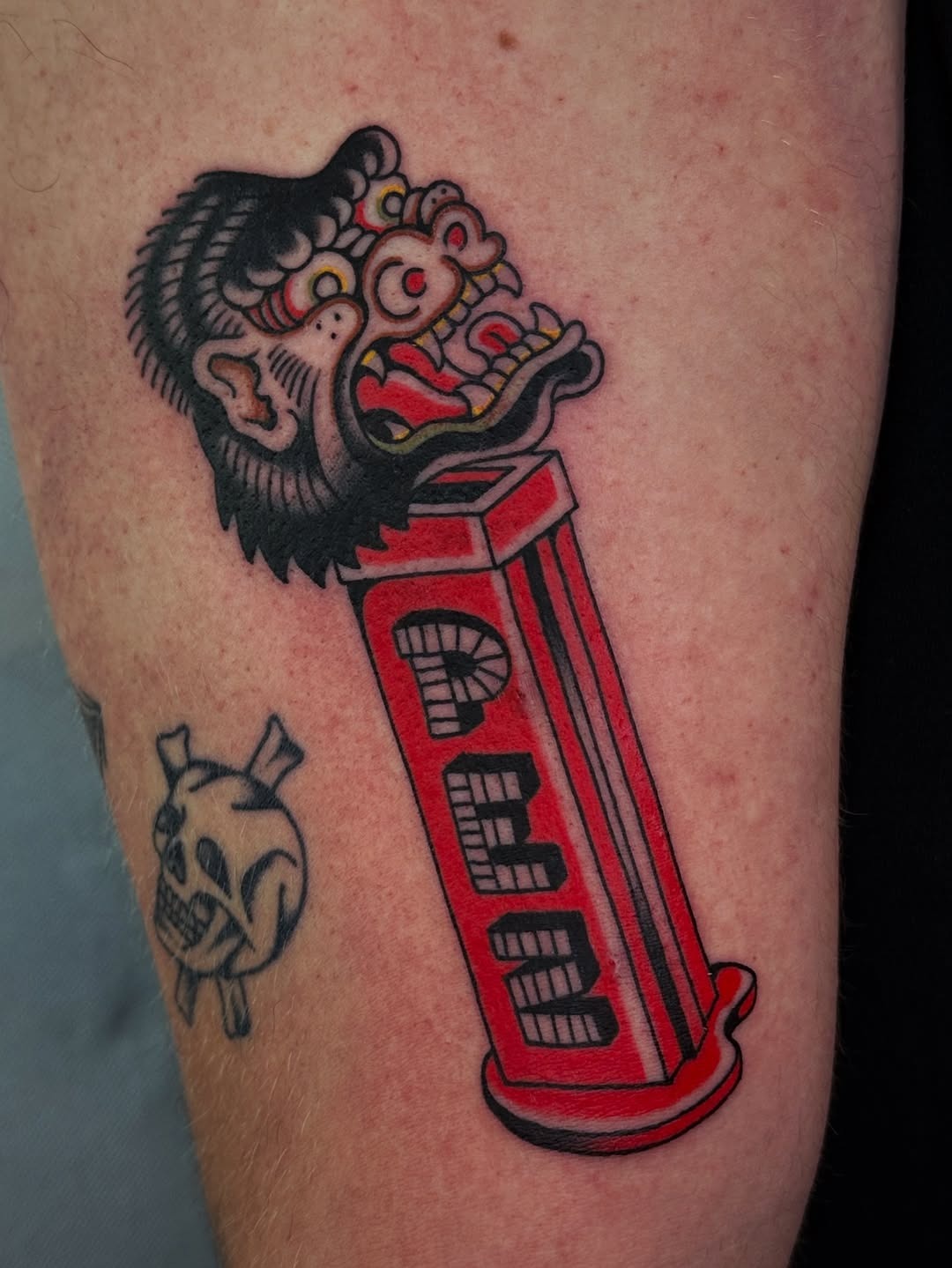 This striking tattoo features a bold gorilla head emerging from a colorful capsule.