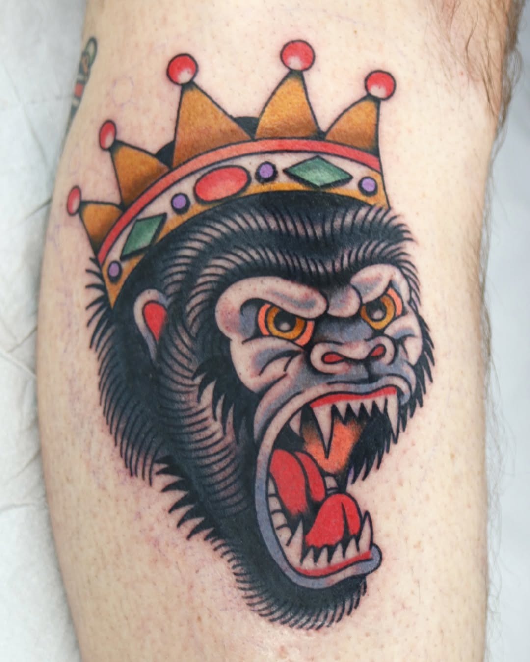 This striking tattoo showcases a fierce gorilla head adorned with a crown.