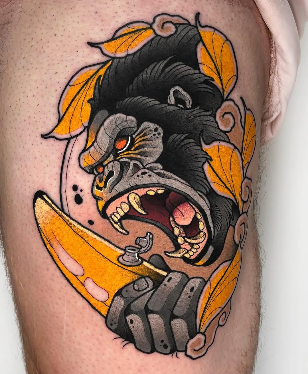 This stunning gorilla tattoo showcases a fierce expression, surrounded by orange leaves.