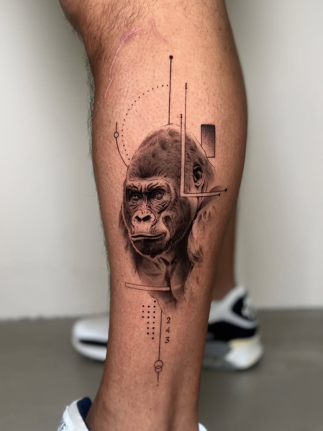 This striking leg tattoo features a detailed gorilla portrait that exudes strength and calmness.