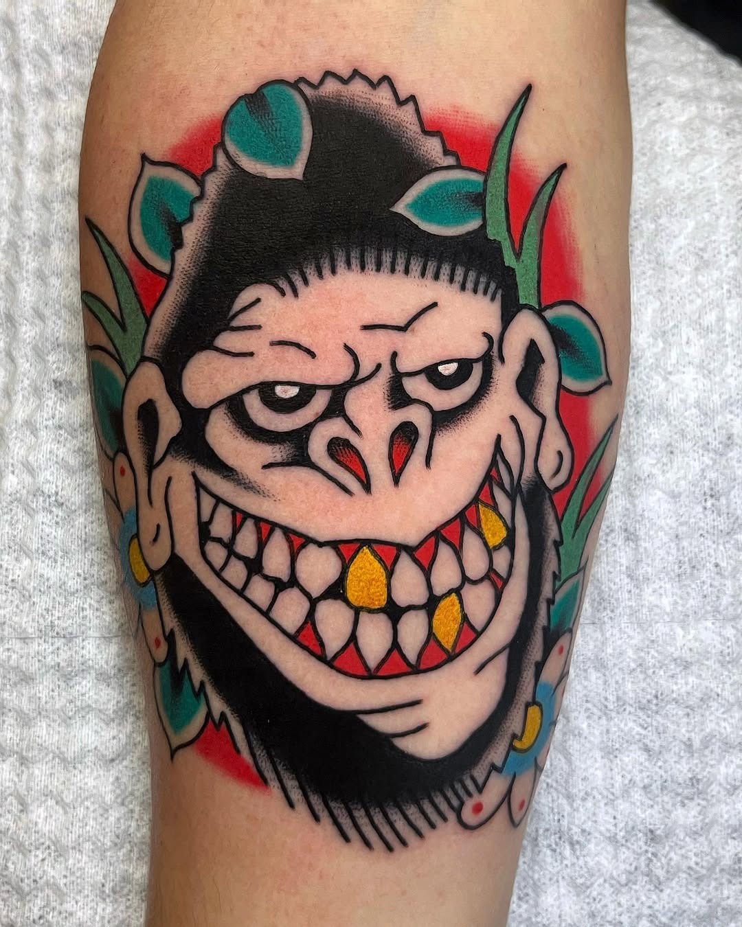 This tattoo features a cartoonish gorilla with a playful expression, showing sharp teeth and a mischievous smile.