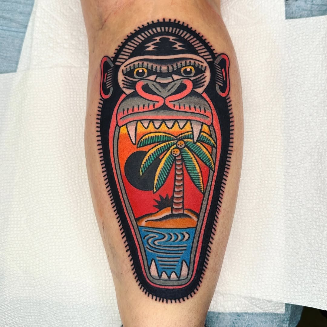 This striking gorilla tattoo showcases a vivid landscape within its mouth, combining elements of nature with a fierce expression.