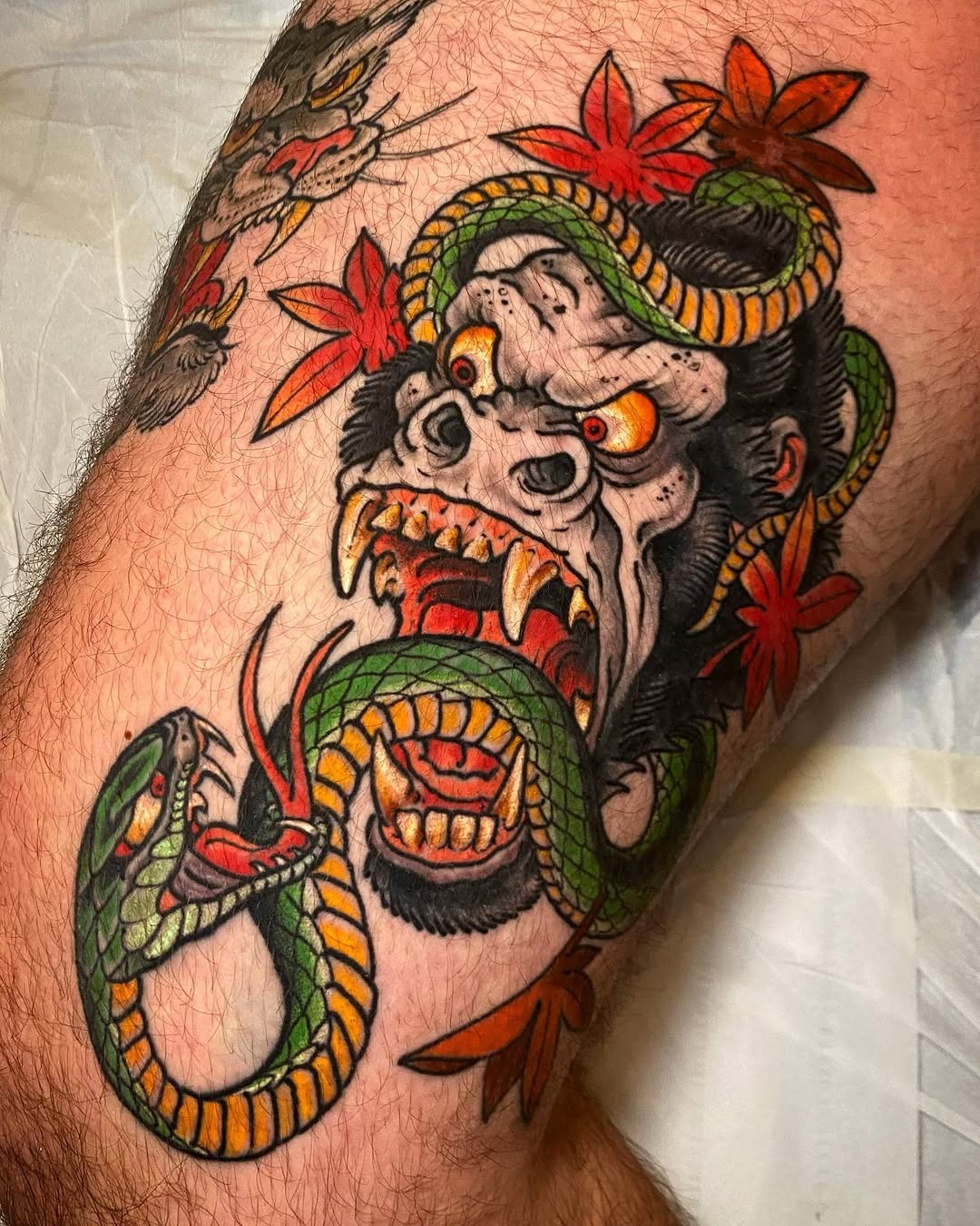 This striking tattoo features a gorilla with an intense expression, its mouth wide open as it battles a serpent.