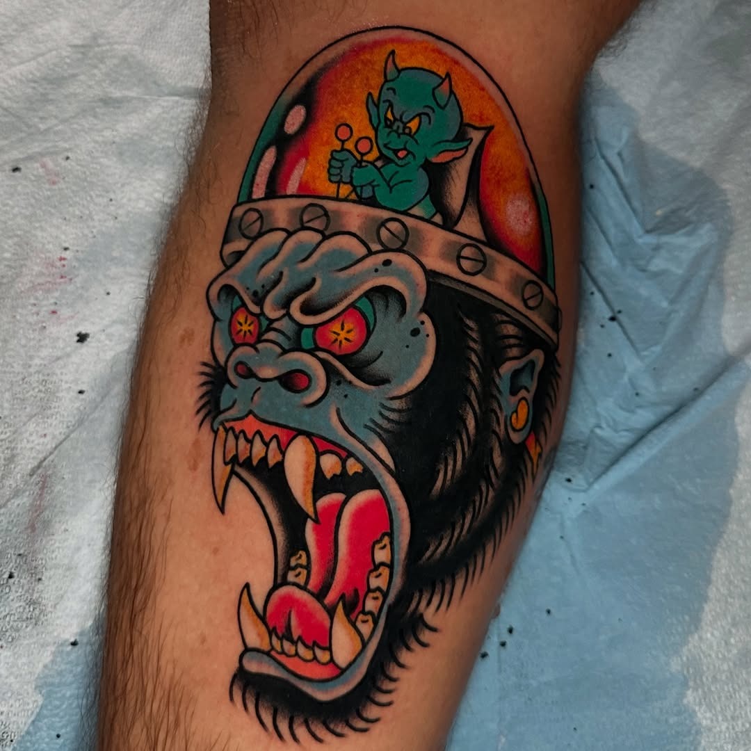 This striking tattoo features a fierce gorilla's face with bright blue and yellow accents.