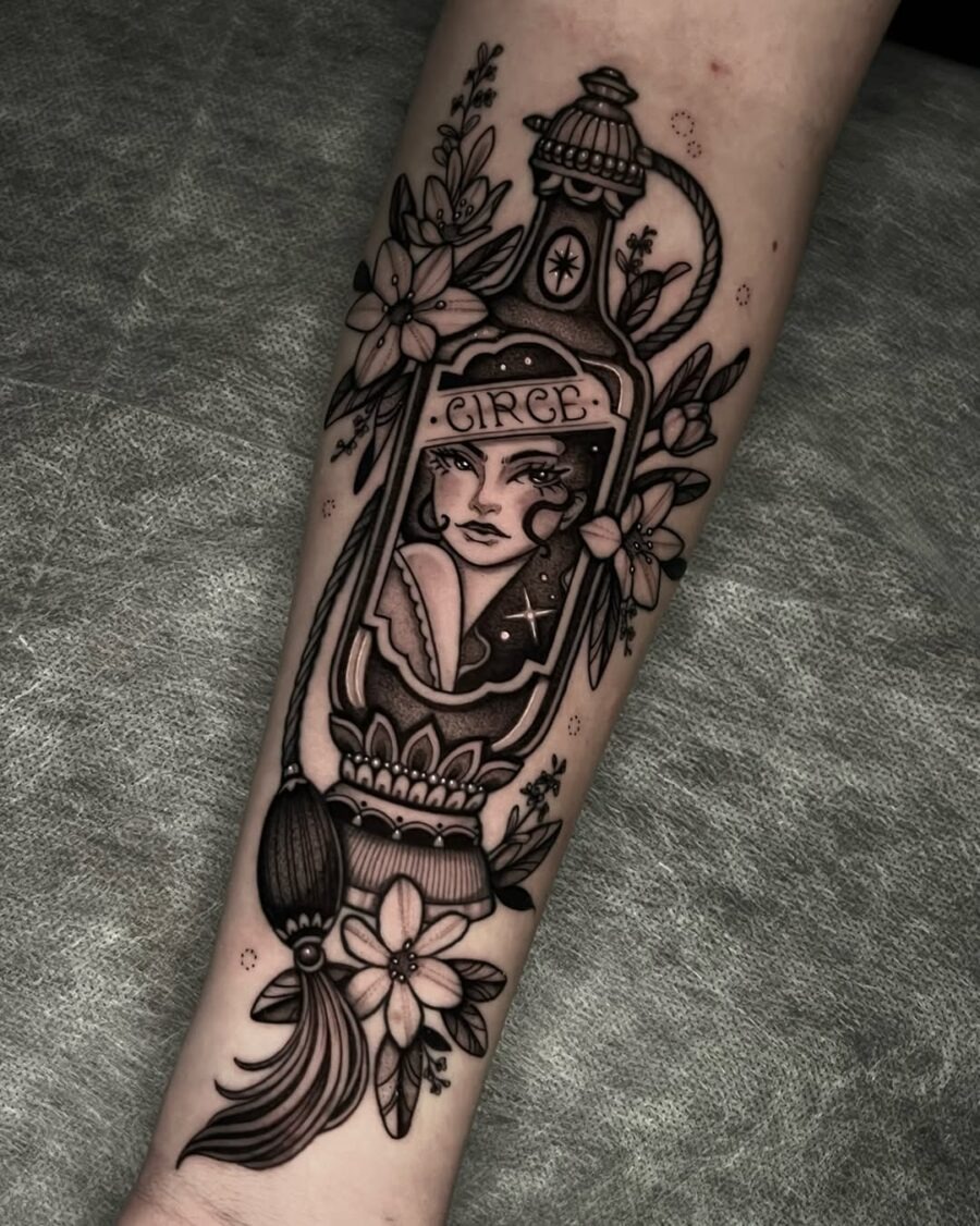 This tattoo features a striking female portrait encased in a beautifully detailed ornate bottle, adorned with delicate flowers and intricate designs.