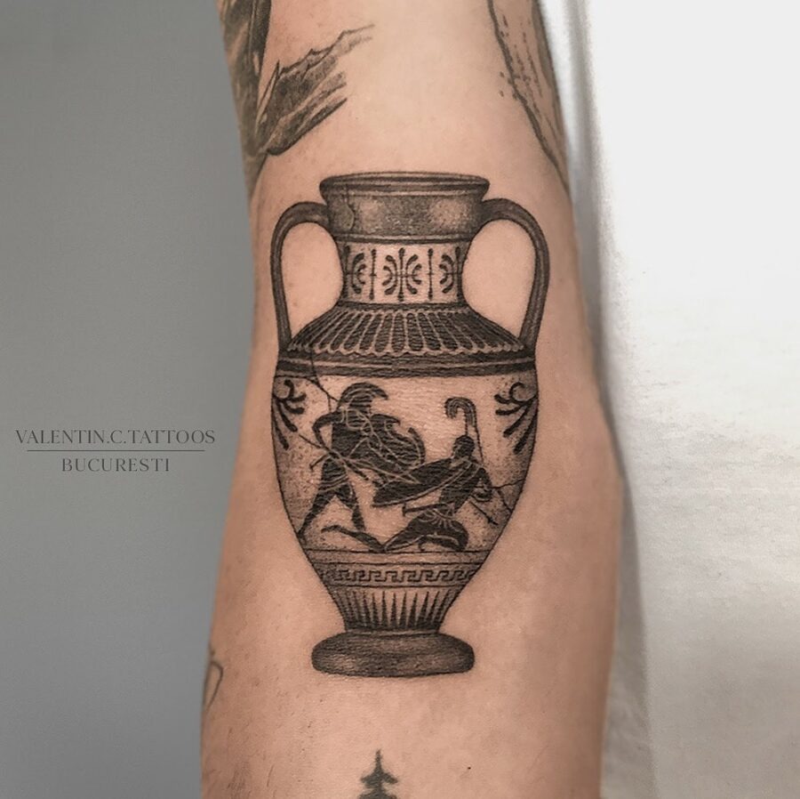This tattoo showcases a beautifully designed Greek vase featuring figures from mythology, intricately detailed to capture the essence of ancient art.