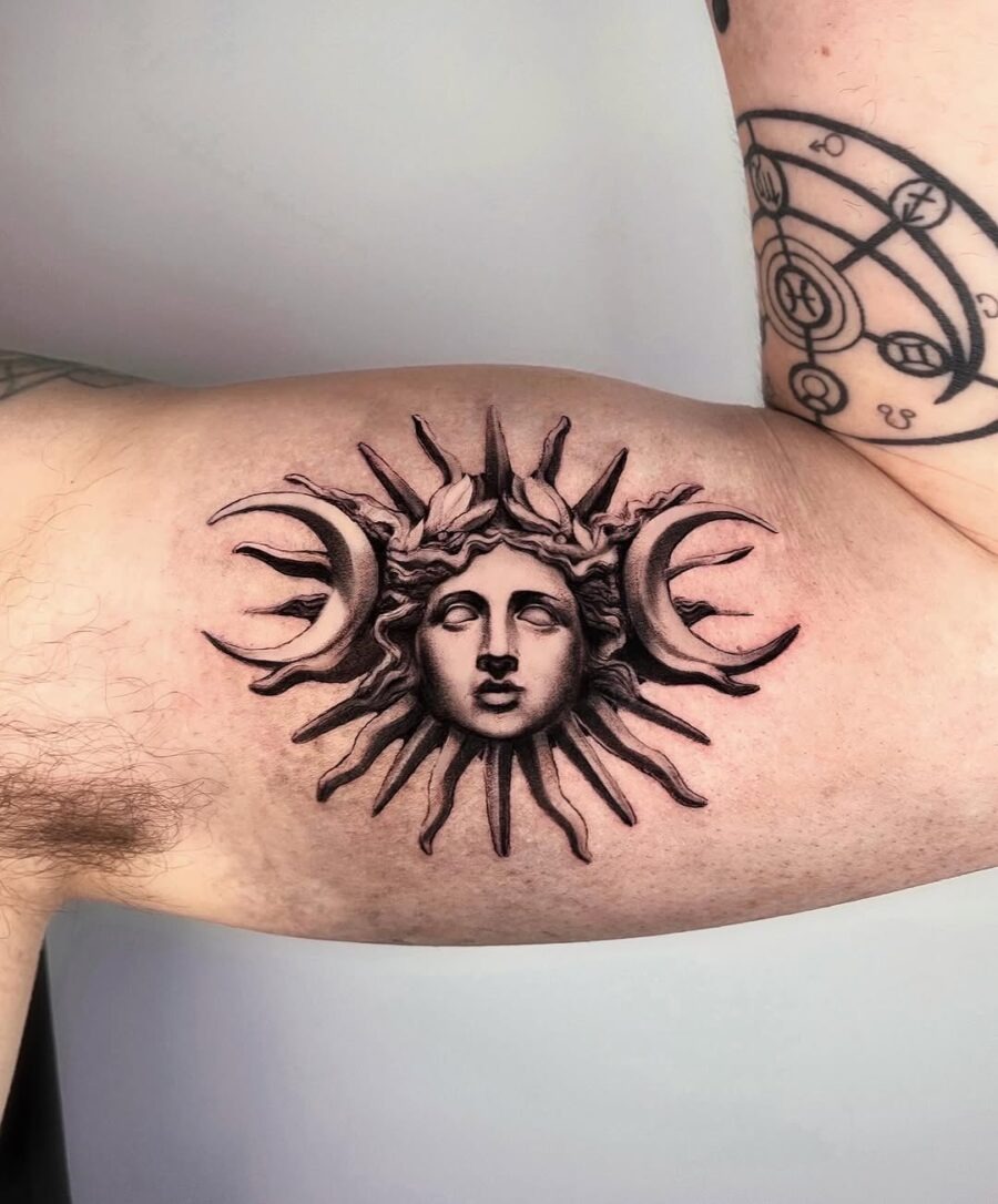 This tattoo showcases a beautifully detailed depiction of a divine figure surrounded by the sun and crescent moons.