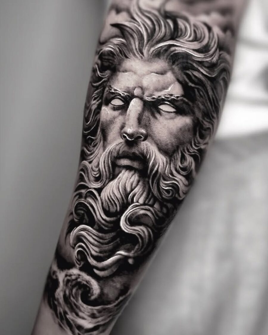 This tattoo features a striking dark portrait of Zeus, showing intricate details in his flowing hair and beard.