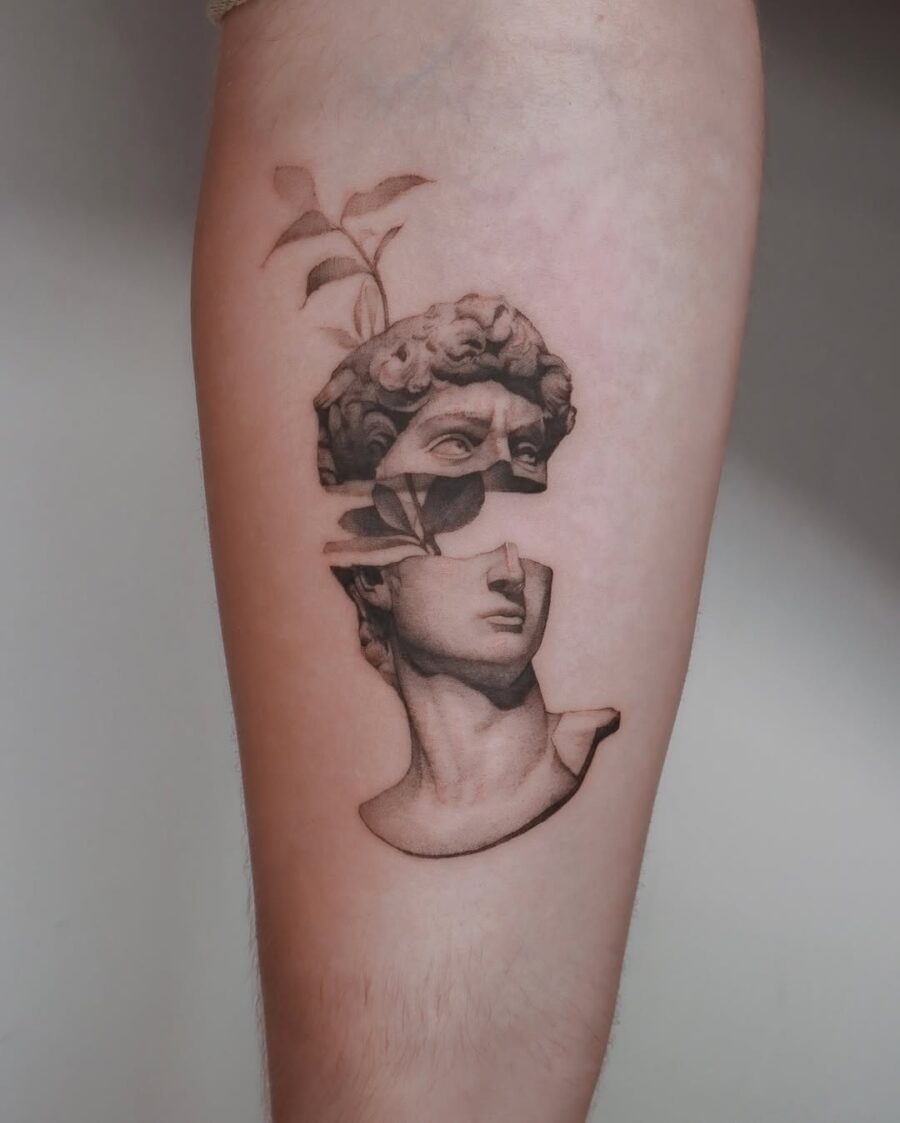 This tattoo features a stunning representation of Michelangelo's David, artistically depicted with a floral element emerging from its crown.