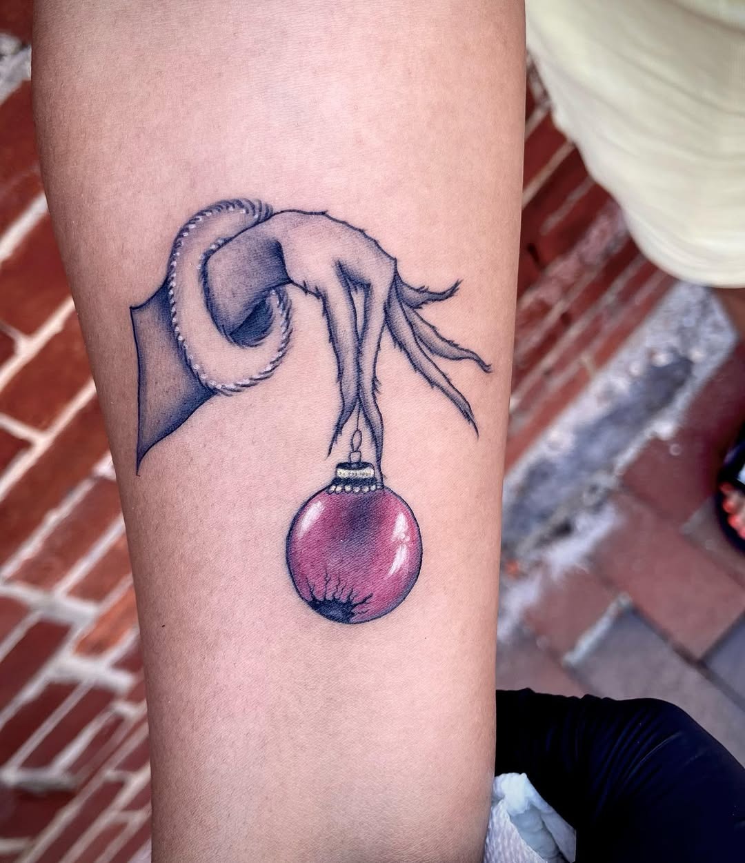 Whimsical Grinch hand with hanging ornament Tattoo Design