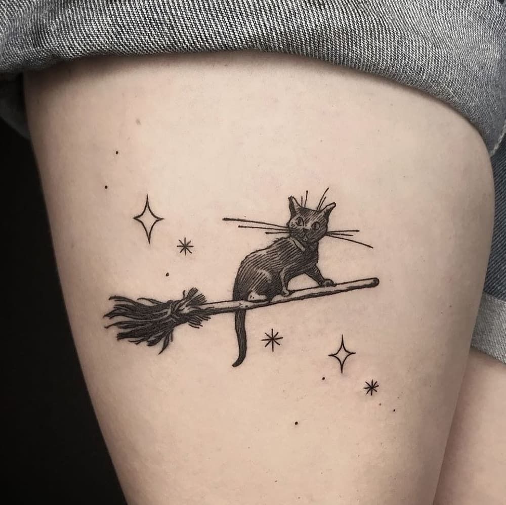 Cat on a Broomstick, a tattoo design rendered in clean detailed linework for the leg.