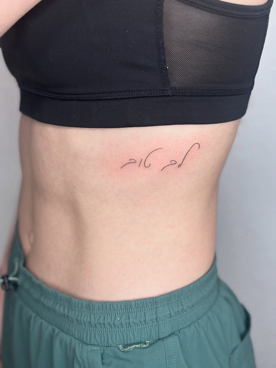 Elegant Hebrew Script Tattoo on Rib Tattoo Design