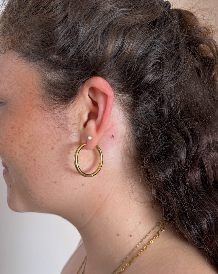 Subtle ear tattoo peeking from behind hair Tattoo Design