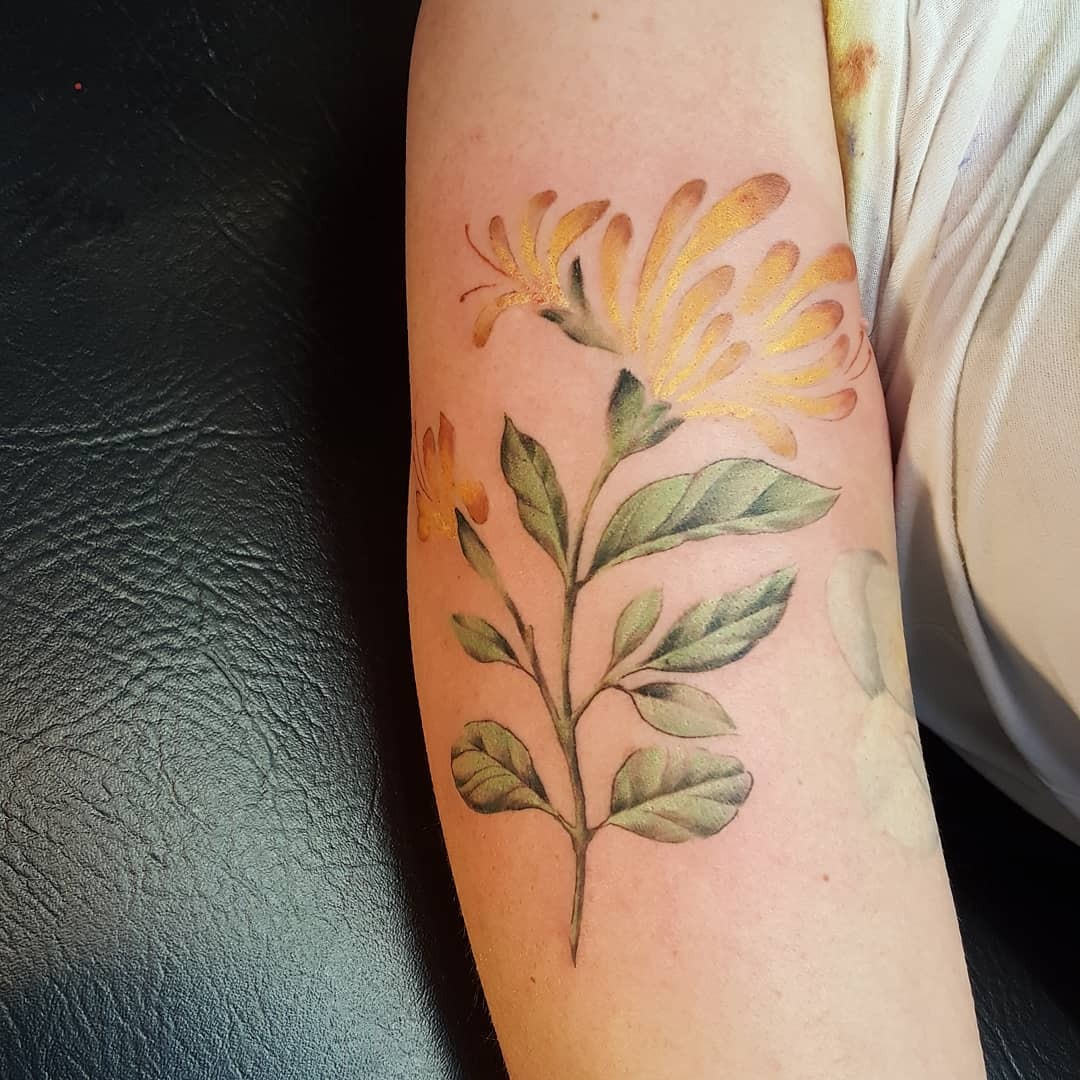 This honeysuckle tattoo beautifully blends soft yellows and greens.