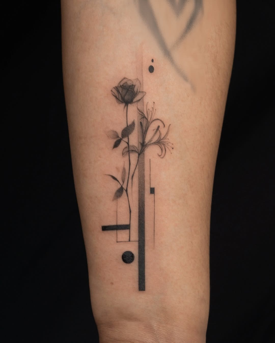 This honeysuckle tattoo features a sleek black line design with delicate floral elements.