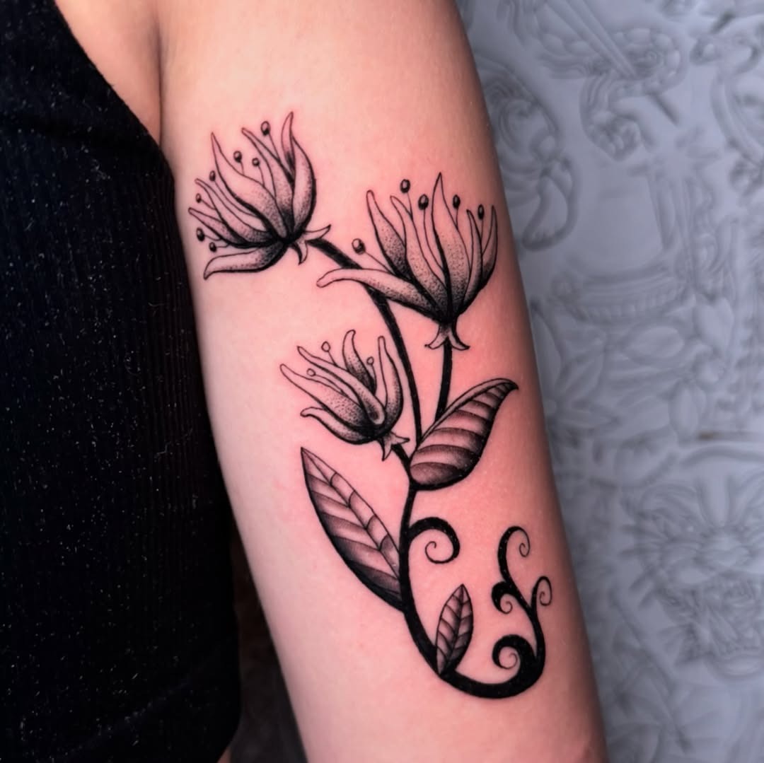 This stunning honeysuckle tattoo features delicate black line work, beautifully capturing the intricate details of the flowers and foliage.