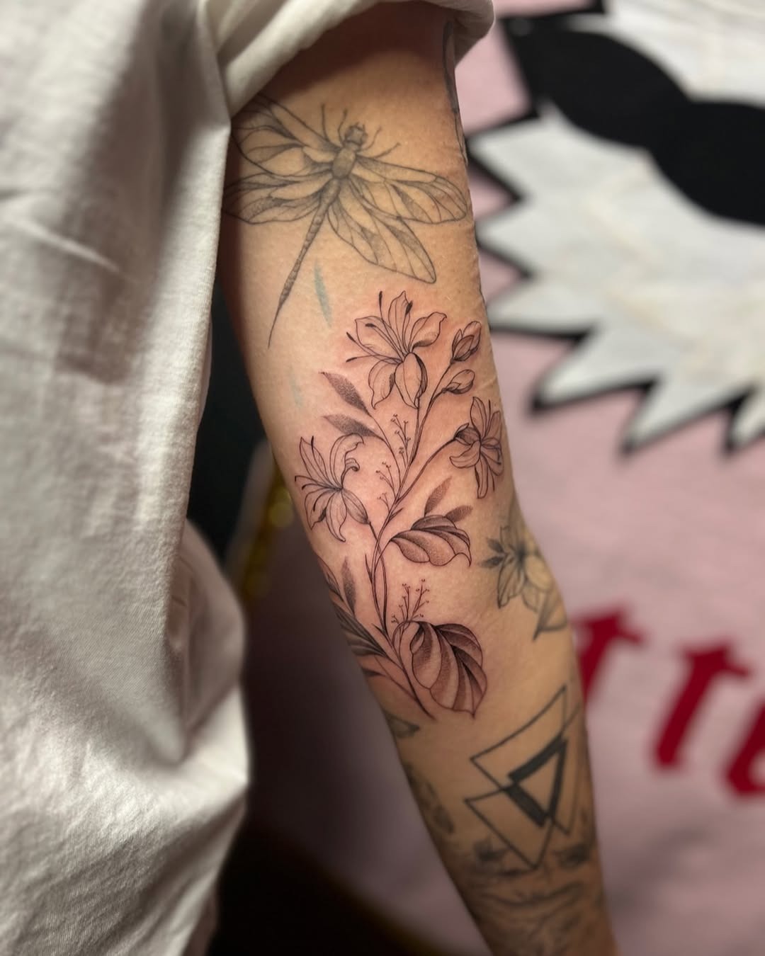 This honeysuckle tattoo features intricate floral designs that flow gracefully along the arm.