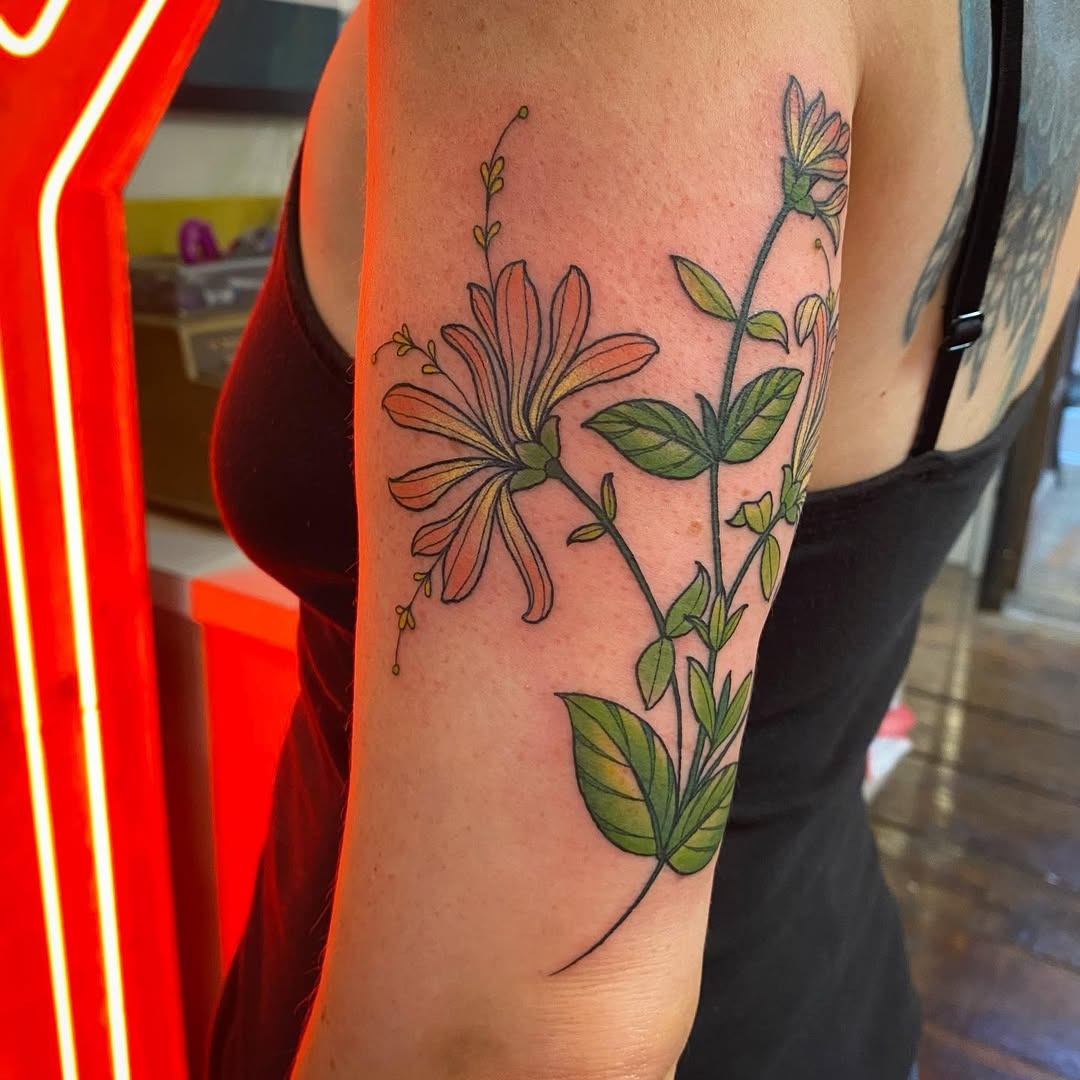 This tattoo features a beautiful honeysuckle design, showing its delicate flowers and green leaves.