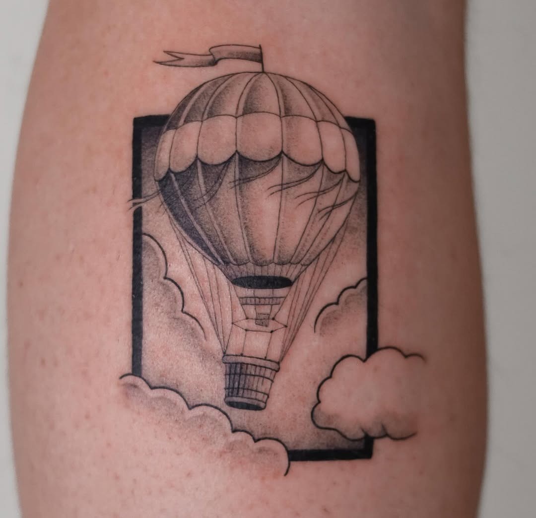 This striking tattoo features a beautifully detailed hot air balloon surrounded by fluffy clouds.