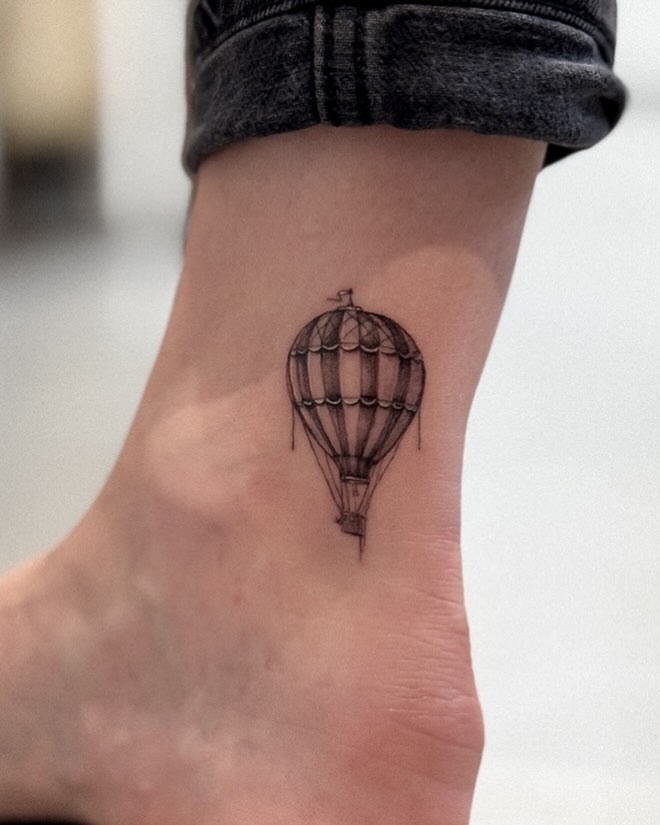 This intricate hot air balloon tattoo features delicate details and a monochrome palette.