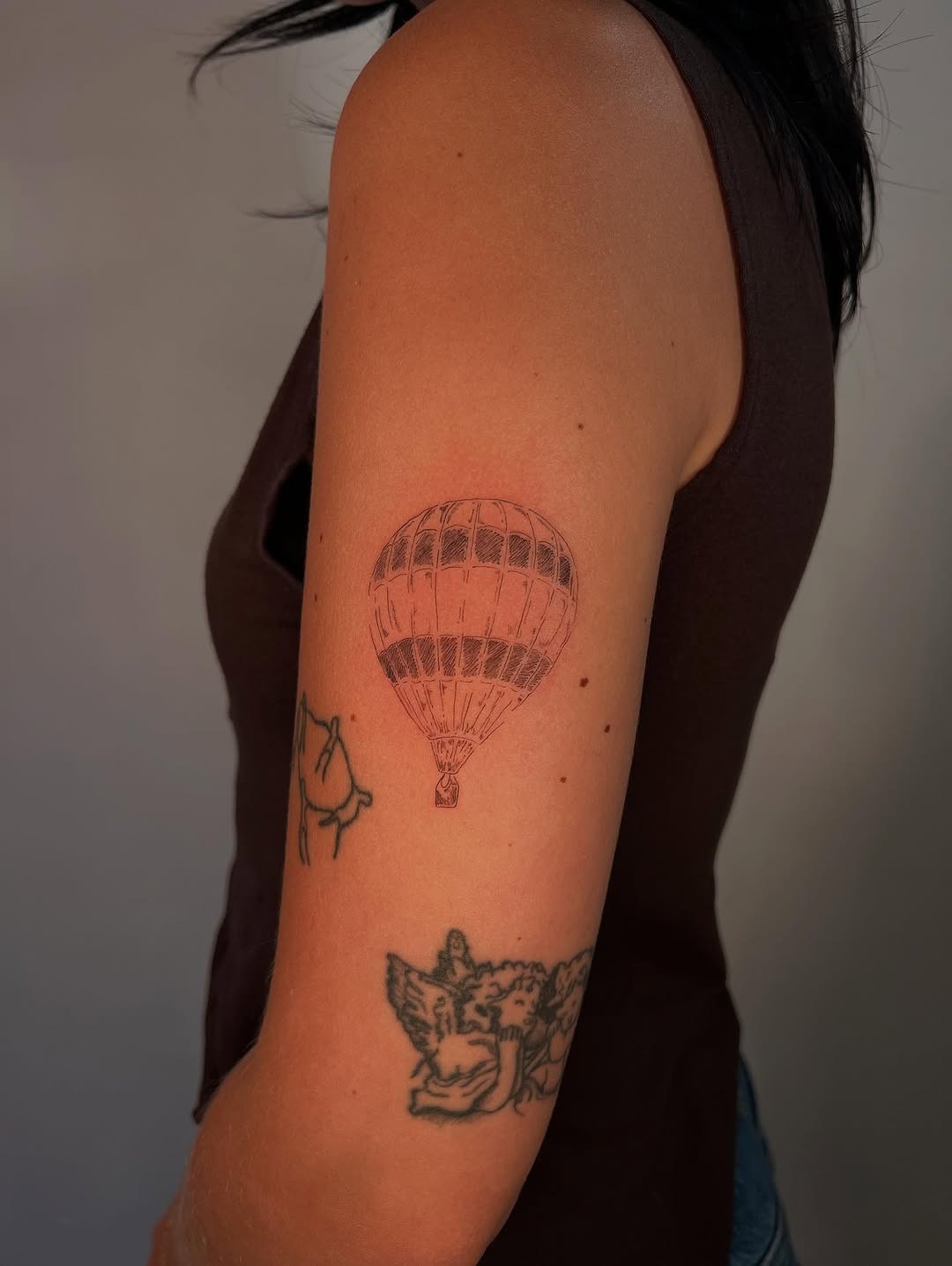 This tattoo features a delicately drawn hot air balloon on the upper arm, showing its intricate details.