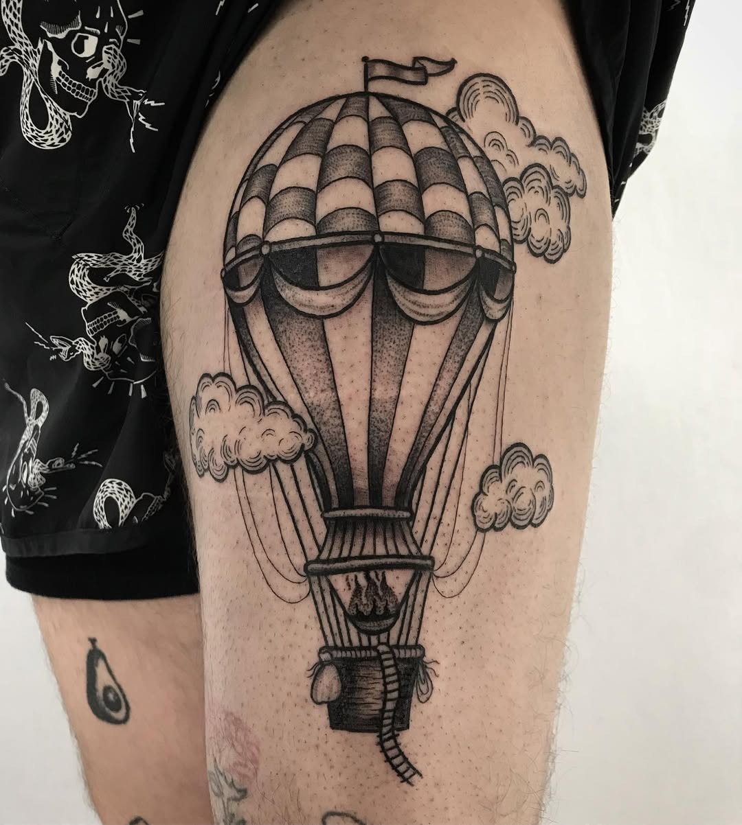 This tattoo features a beautifully detailed hot air balloon nestled among fluffy clouds.