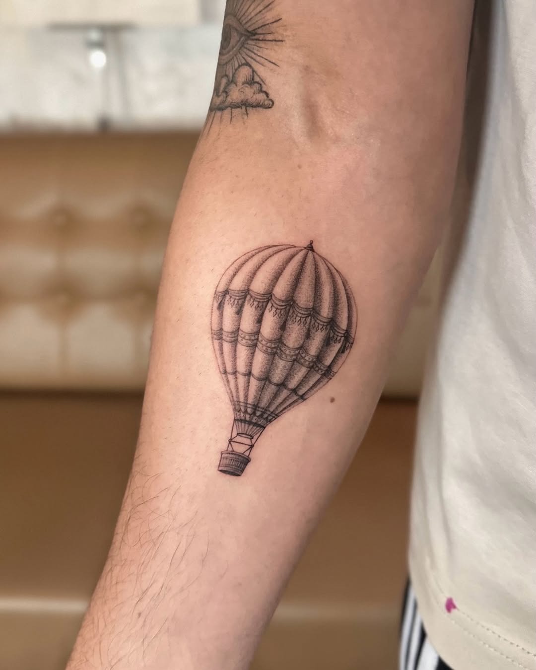This tattoo features a beautifully detailed hot air balloon, showing delicate line work and intricate shading.