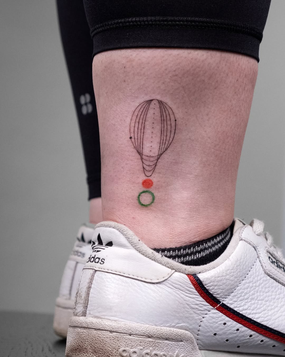 This tattoo showcases a delicate, minimalist hot air balloon design with clean lines.