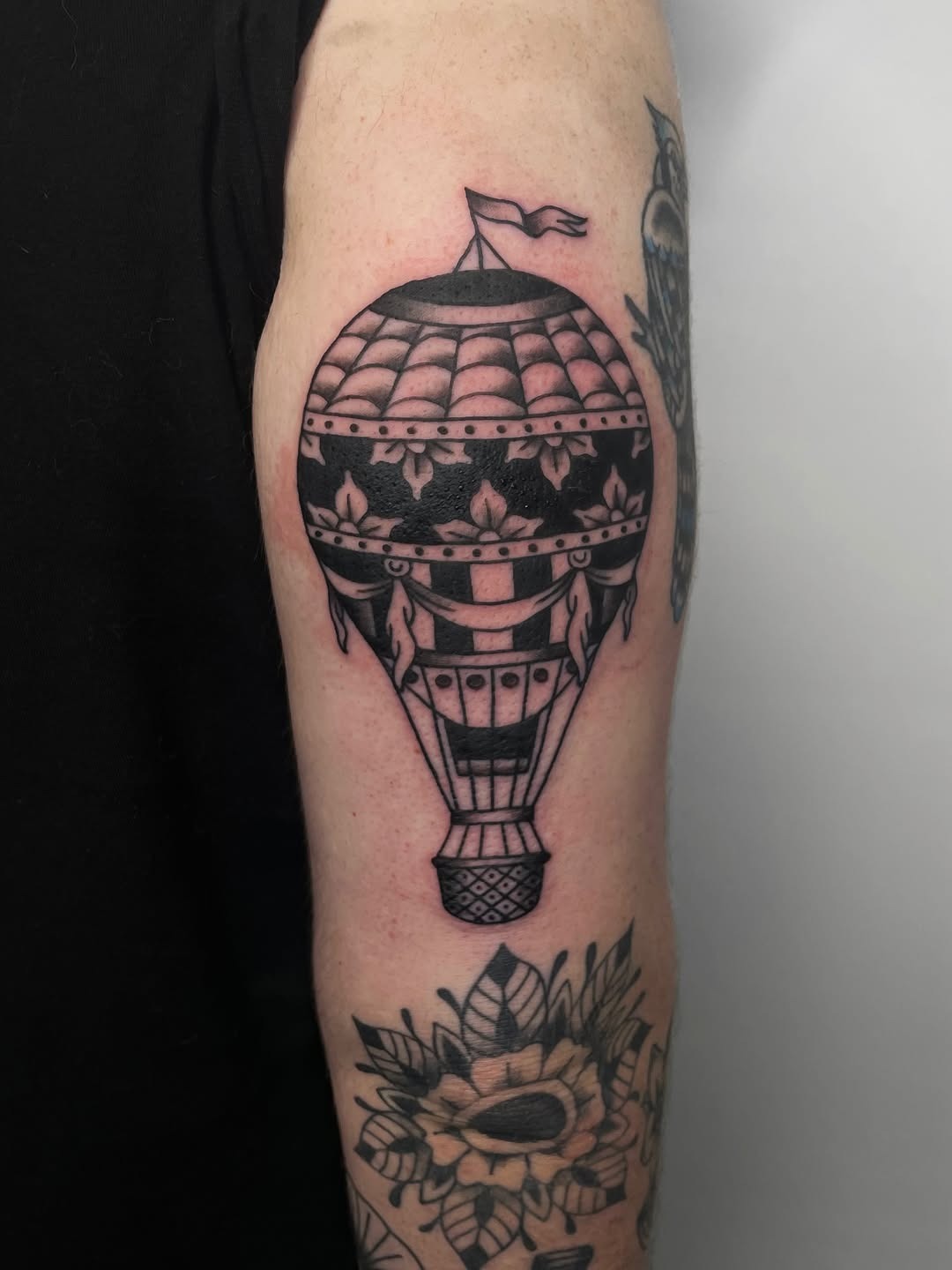 This tattoo showcases a beautifully detailed hot air balloon in black ink.