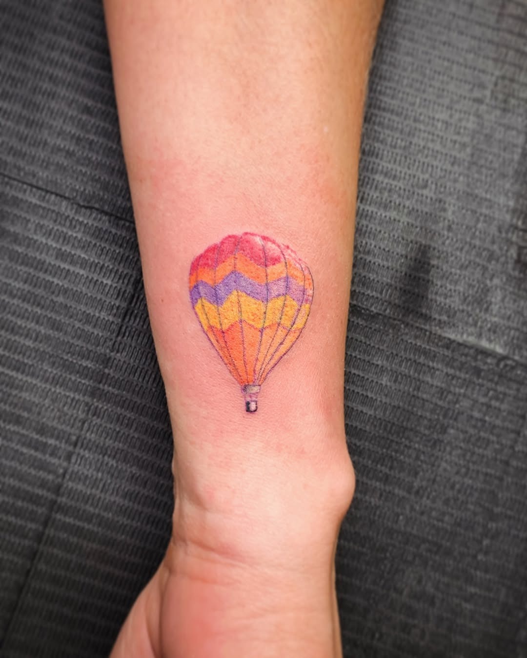 This colorful hot air balloon tattoo features a blend of warm hues, bringing a cheerful vibe.