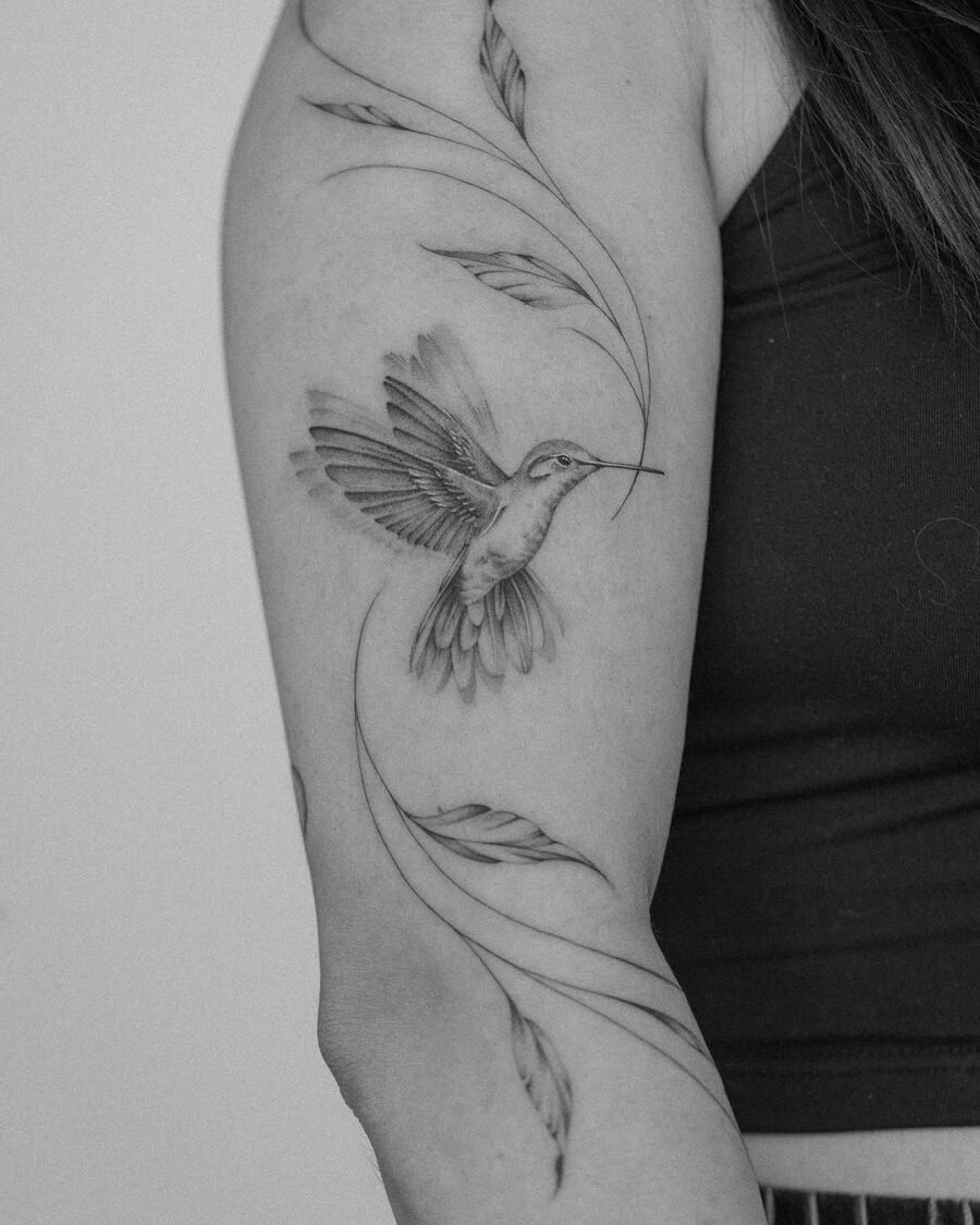 A delicate hummingbird tattoo with flowing leaves Tattoo Design