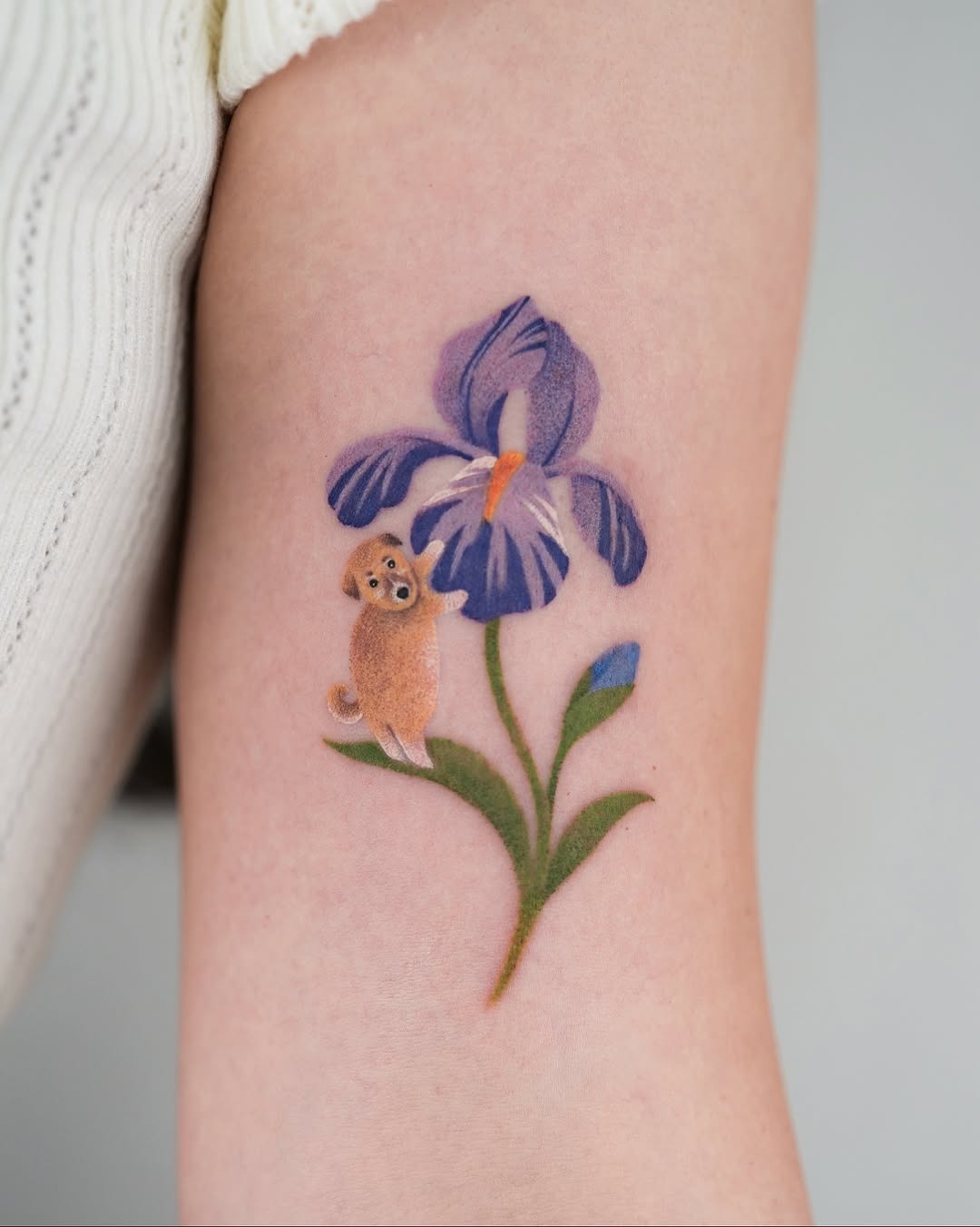 This iris tattoo features colors and delicate details, showing the beauty of the flower and a cute dog companion.