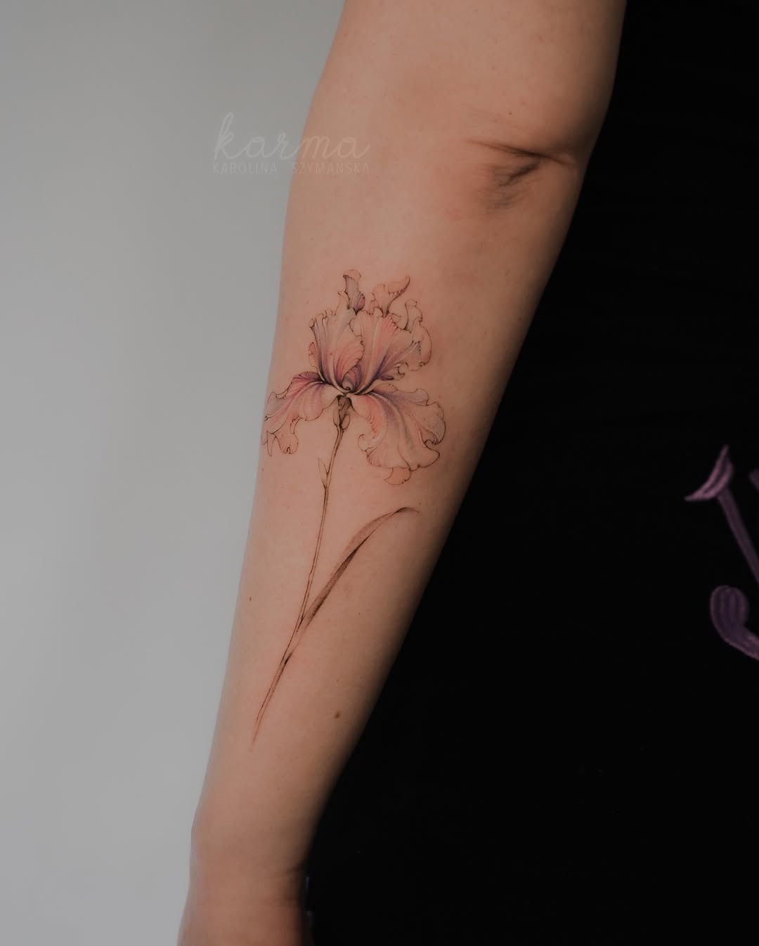 This exquisite iris tattoo beautifully graces the forearm, showing delicate lines and soft colors.