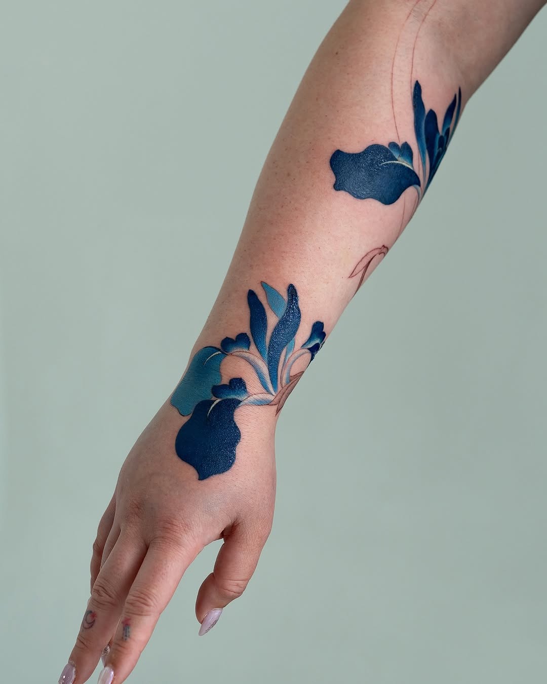 This stunning iris tattoo showcases deep blue hues with intricate floral details.