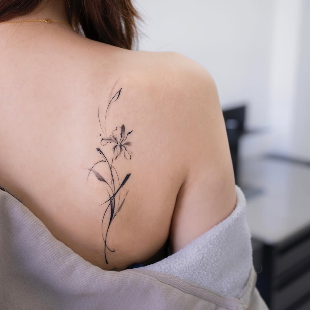 This tattoo features a delicate iris, symbolizing beauty and strength.