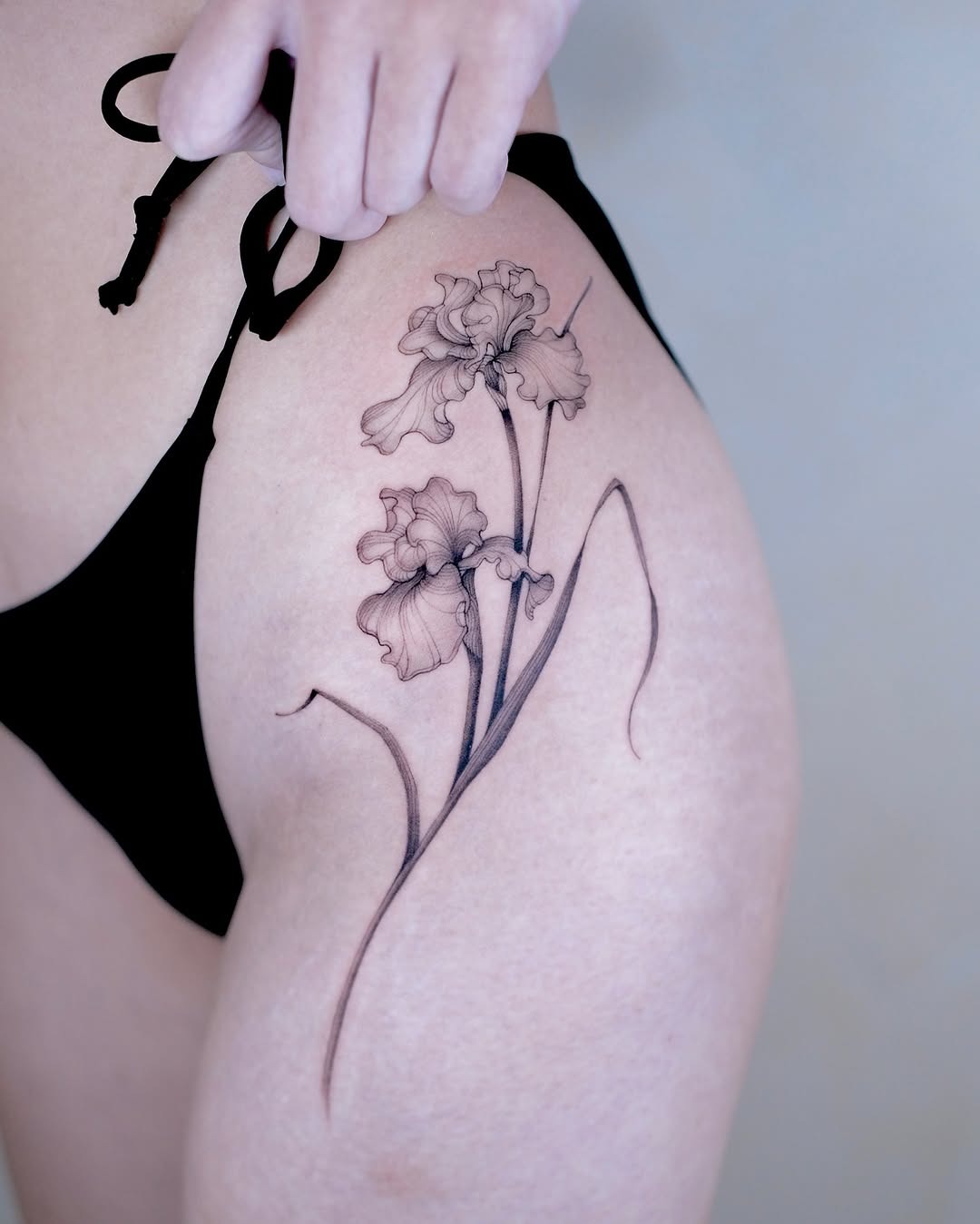 This tattoo features a beautifully detailed iris flower on the upper arm, exuding a feminine charm.