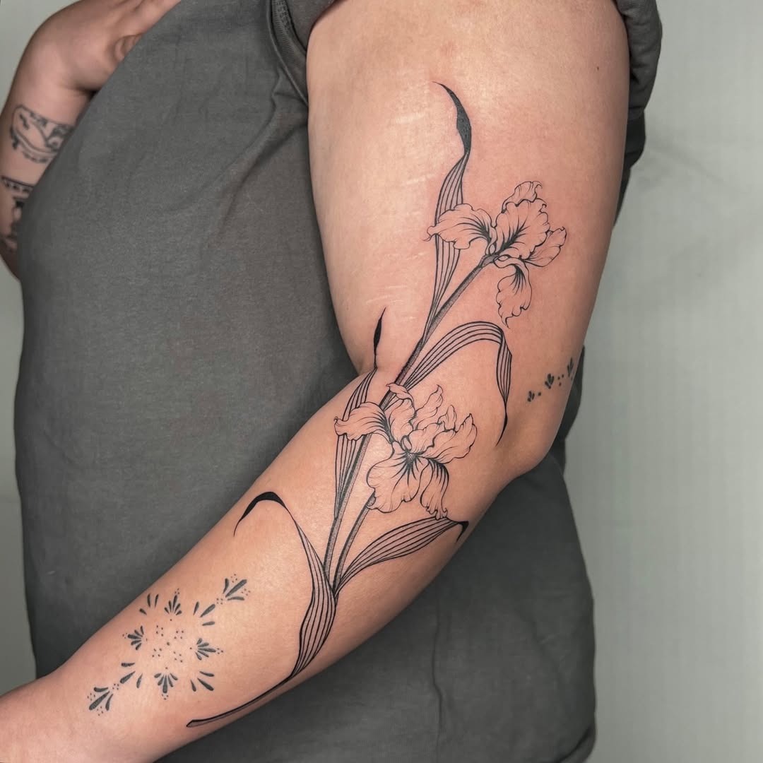 This iris tattoo features delicate black line art that gracefully wraps around the arm.