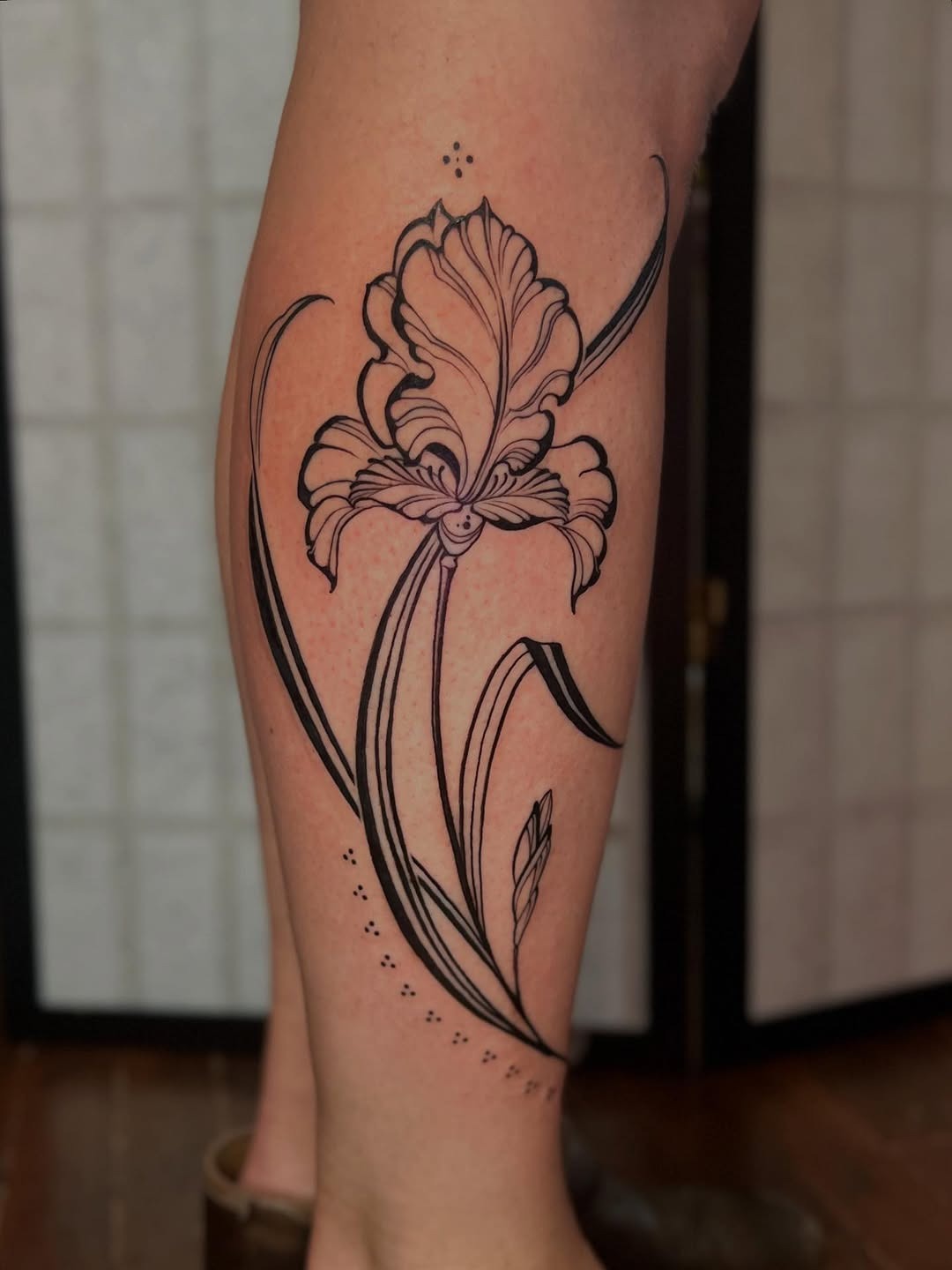 This stunning iris tattoo features detailed linework that flows gracefully along the leg.