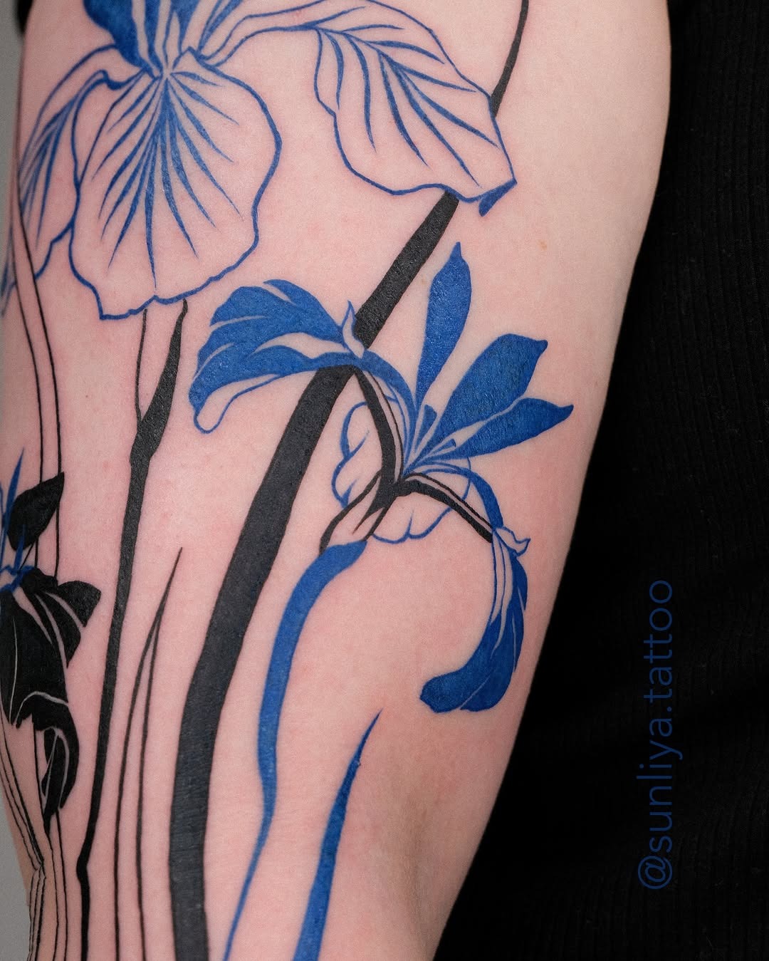 This beautiful iris tattoo features blue hues paired with bold black outlines.