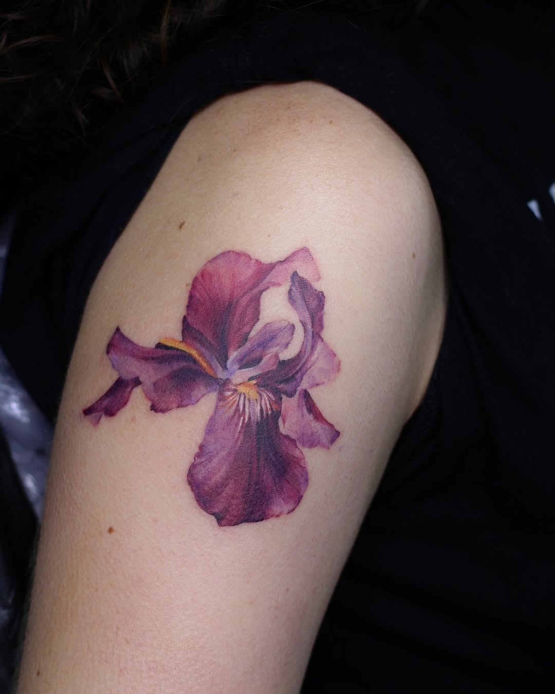This iris tattoo showcases stunning purple hues, perfectly capturing the flower's delicate elegance.