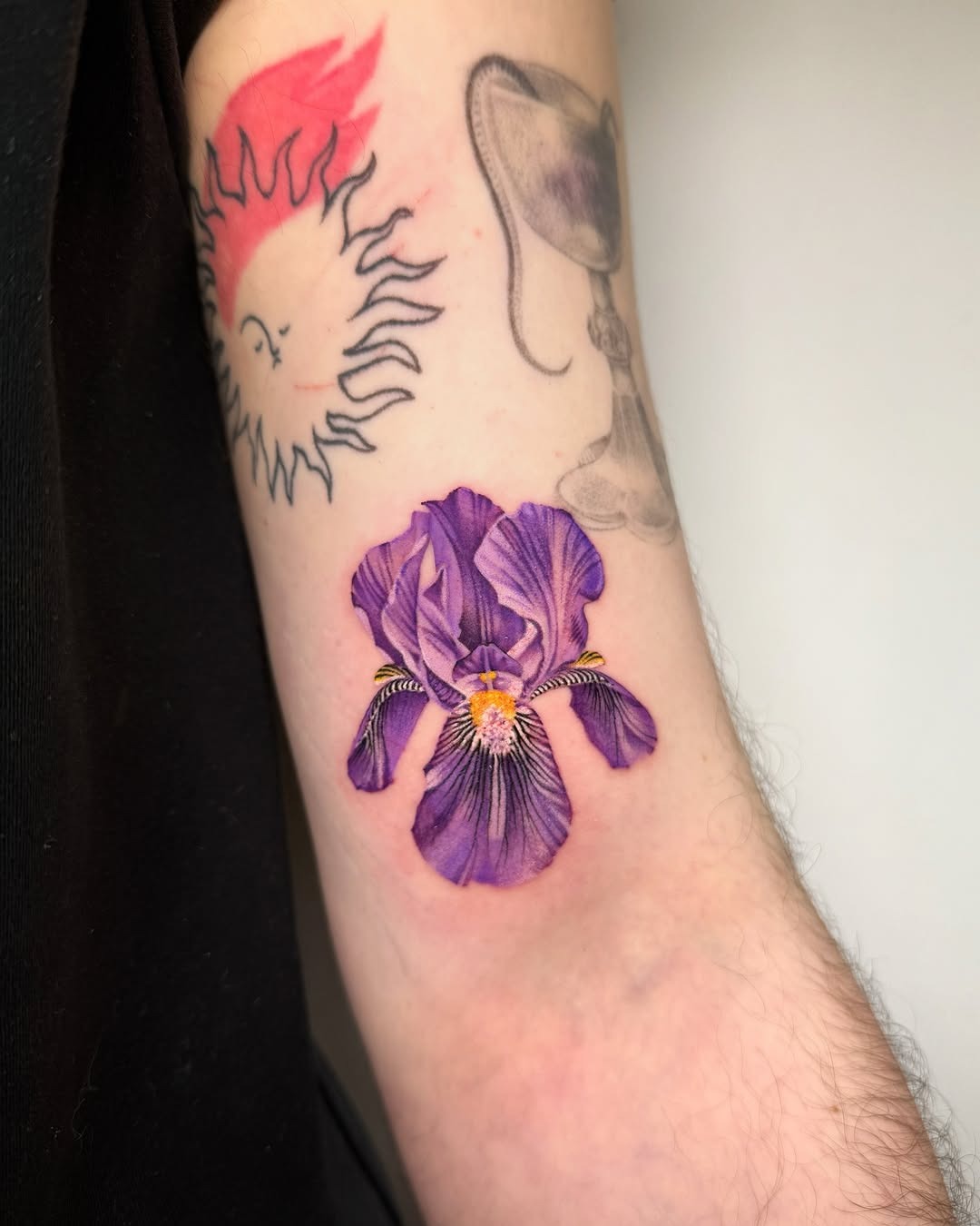 This tattoo features a beautifully detailed iris flower, capturing the essence of its natural beauty.