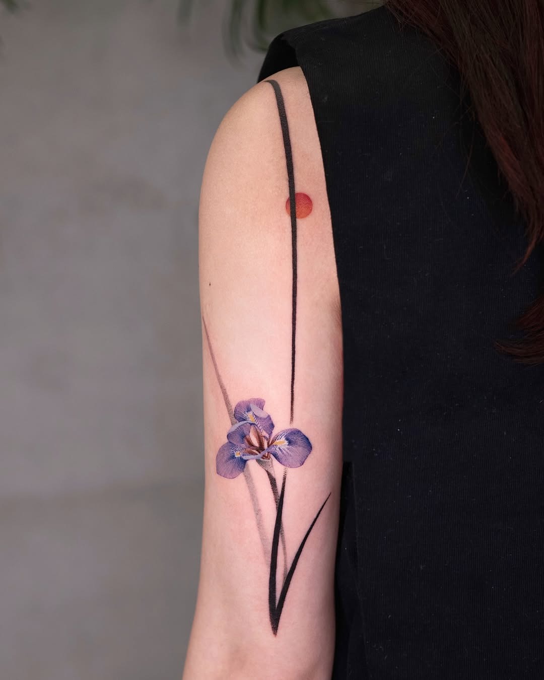 This iris tattoo features purple hues that beautifully contrast with a minimalist black outline.