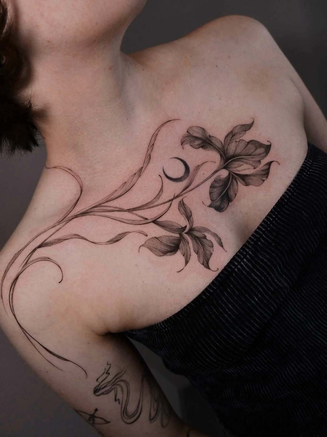 This tattoo features intricate iris flowers gracefully wrapping around the shoulder.