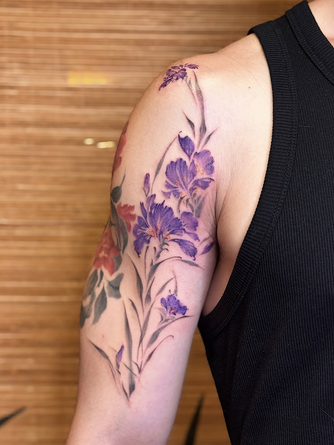 This stunning iris tattoo features purple hues intertwined with delicate floral accents.