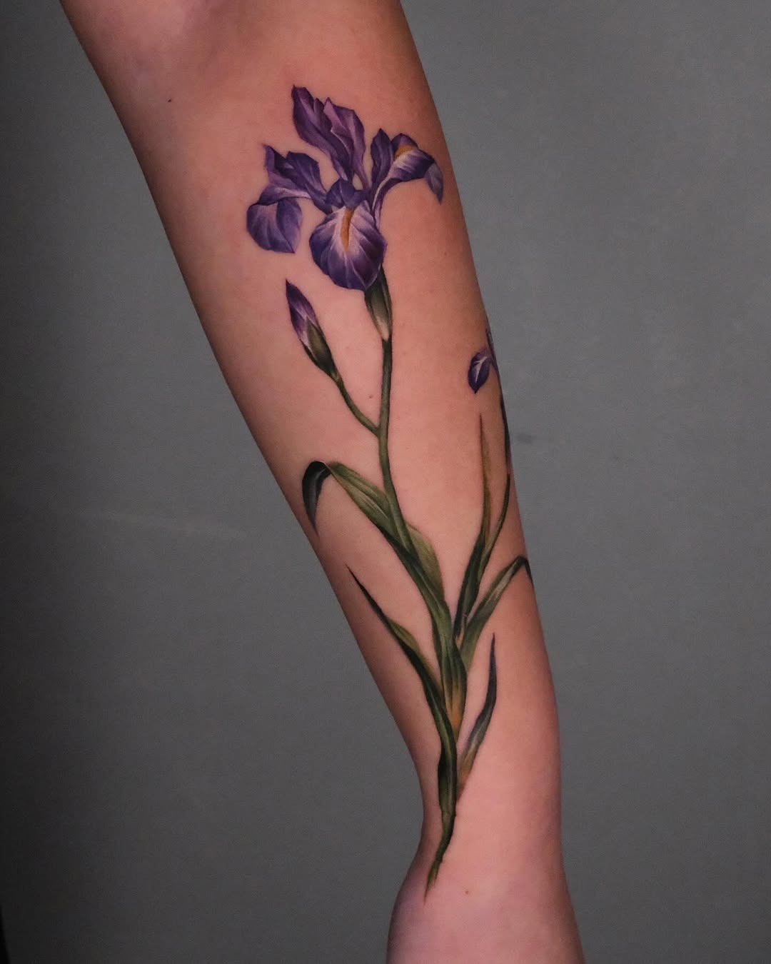This iris tattoo features a stunning representation of the flower in purple.