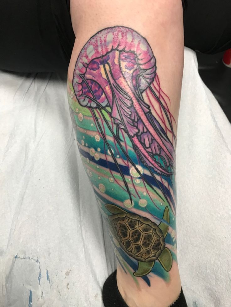 Realistic oceanic tattoo featuring a swimming sea turtle alongside a translucent jellyfish