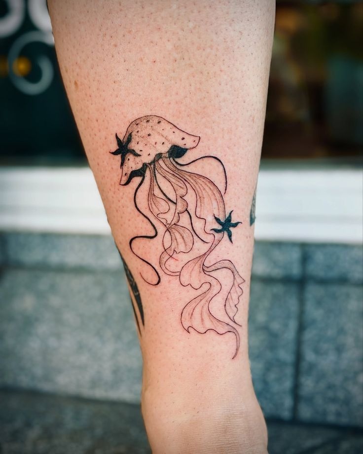 Clean minimalist fine line jellyfish tattoo decorated with tiny starbursts and constellation dots