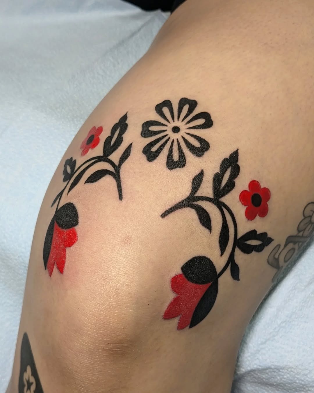 Elegant floral knee tattoo design in black and red Tattoo Design